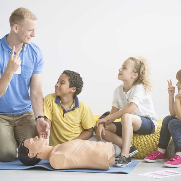 Paramedic,Showing,Two,Fingers,To,Group,Of,Children,During,First
